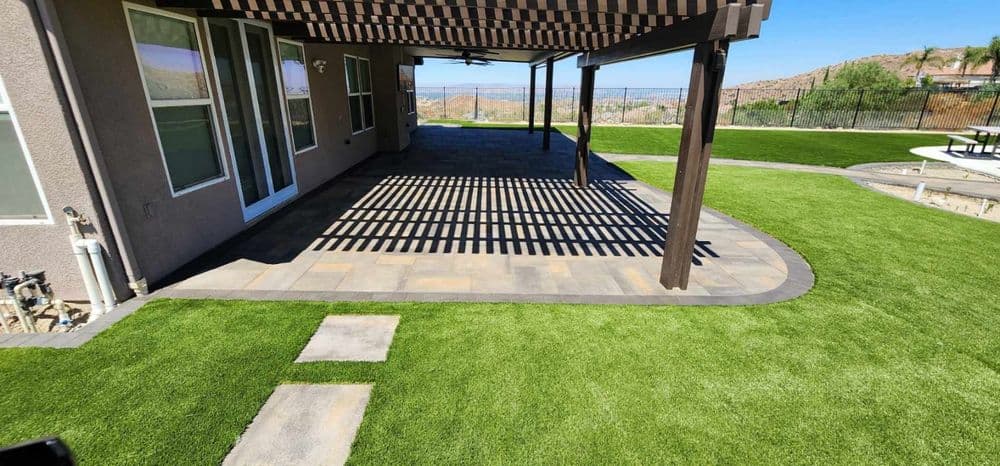 Patio with shaded seating area, artificial grass, and stunning views in the background.