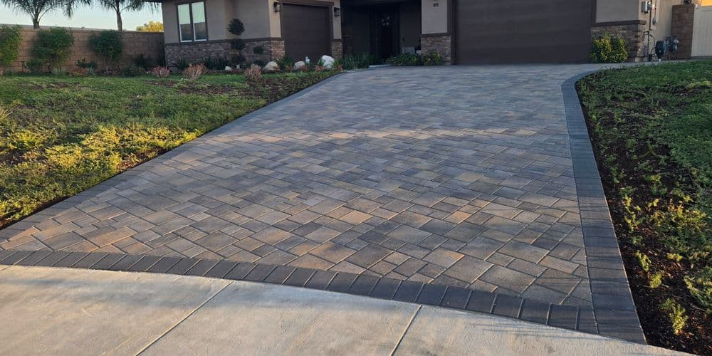 Paved driveway with interlocking stones leading to a modern home entrance.