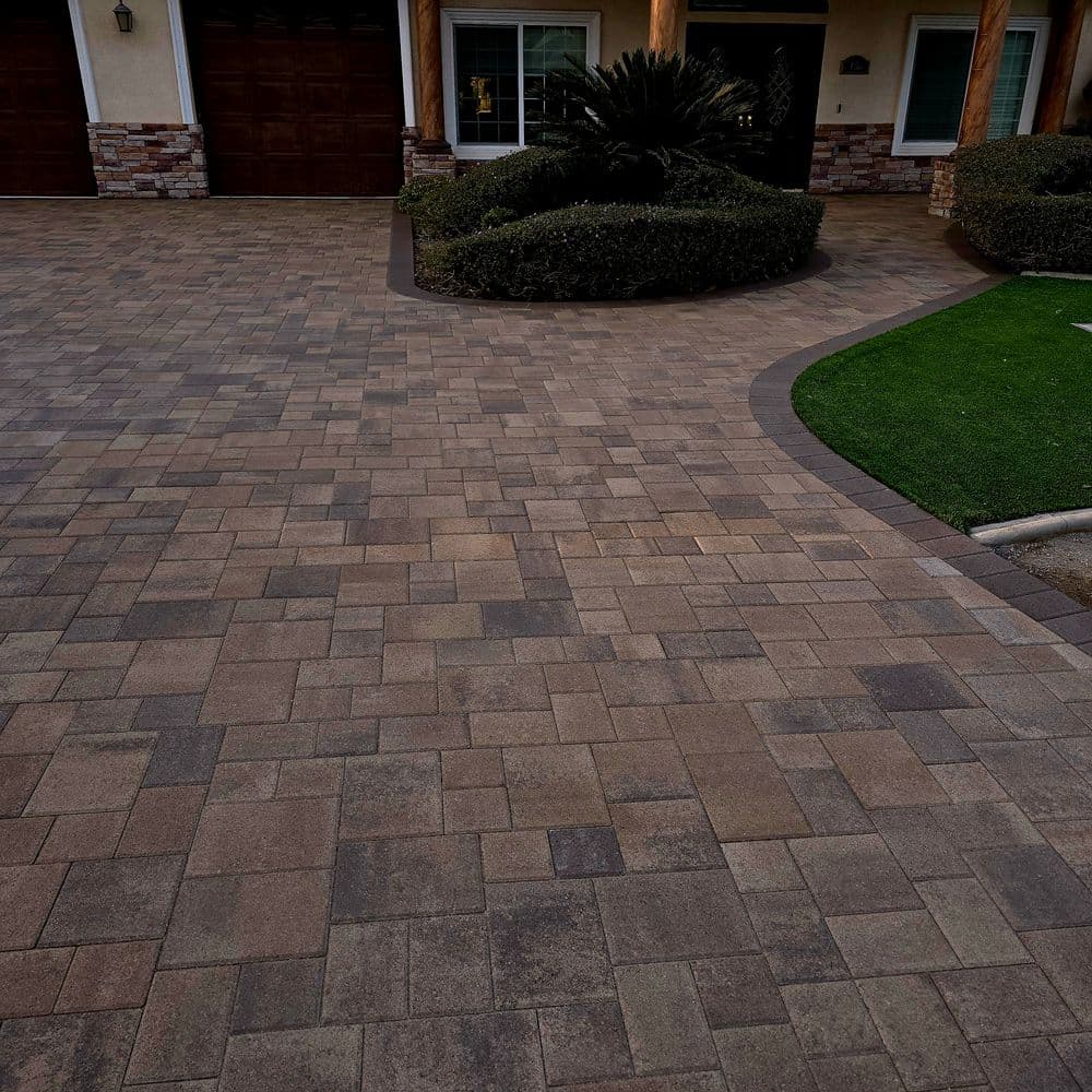 Paver driveway with a curved design and landscaped border near a residential home.