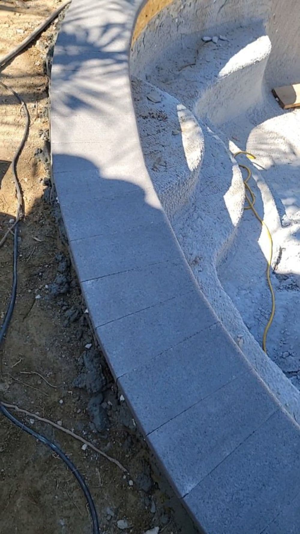 Curved stone pathway edging in a partially constructed landscape feature.