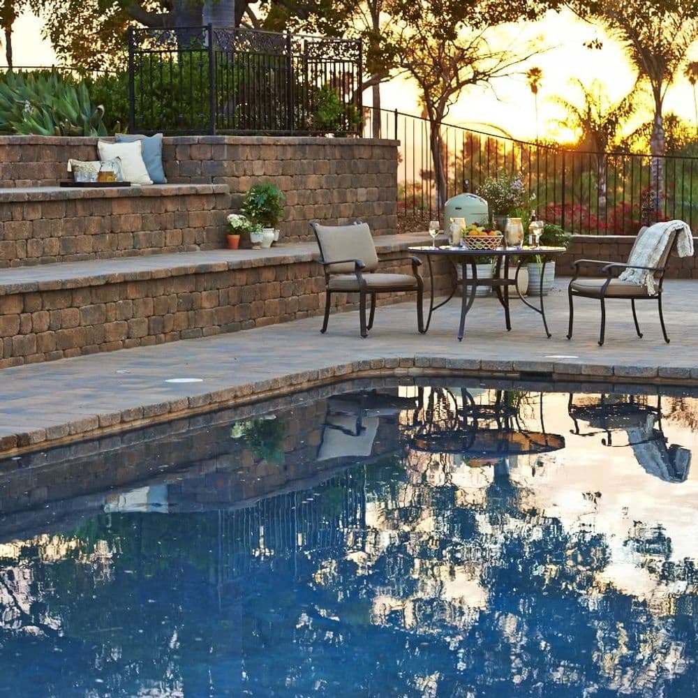 Outdoor pool area with reflection, sunset backdrop, and stylish seating arrangement.