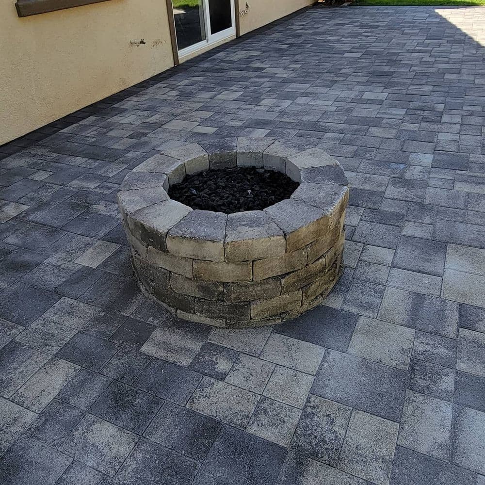 Circular stone fire pit surrounded by a paved outdoor patio.